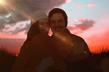 Composite image of portarit of happy couple holding paper heart