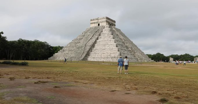 Chichen Itza couple walk towards El Castillo pyramid. Pre Columbian city built by the Maya people in Yucatan, Mexico. One of the largest Maya cities. Most visited archaeological sites in Mexico.