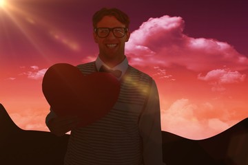 Composite image of geeky hipster holding heart card