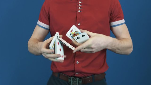 Close up man in red polo shirt on red back ground performing playing card shuffle trick