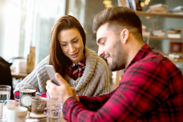 Couple at restaurant looking at his smart phone.