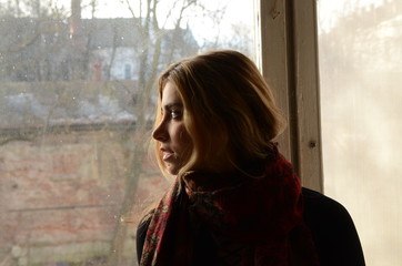 Fototapeta premium beautiful blonde girl in scarf at window in the old house