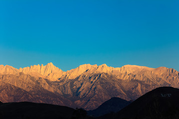 Naklejka premium Early morning sunlight on the peaks of the Mount Whitney range above Lone Pine, California
