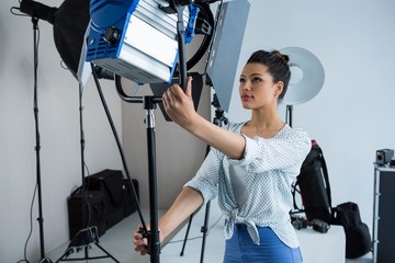 Female photographer adjusting spotlight