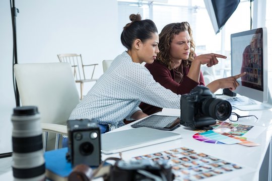 Photographers working over computer - Powered by Adobe