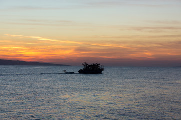 Watching sunrise on the Red Sea coast in Egypt. Fishing boat passing by