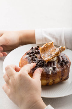 Cannoli donut on a white plate . Kid's hands  holding a plate 