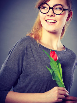 Smiling lady sniffing flower.