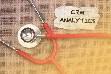 Stethoscope, paper with word “ CRM ANALYTICS “. Medical Concept