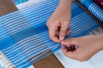 lady's hand weaving a blue fabric