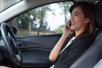 Fototapeta na wymiar Asian woman with mobile phone in her car, woman work in car