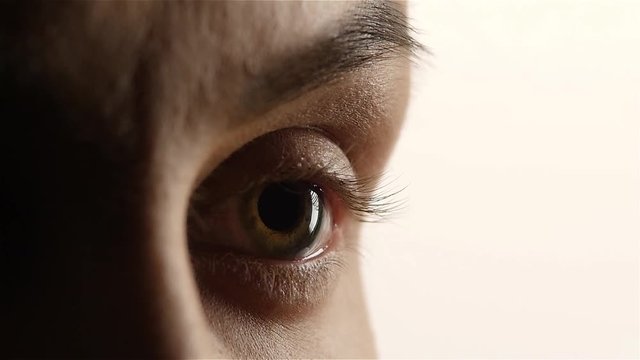 Girl with poor eyesight wear lenses. Close up. White background. Slow motion