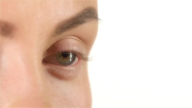 Girl with poor eyesight wear lenses. Close up. White background. Slow motion