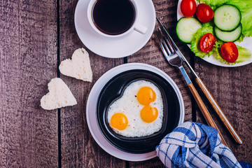 Idea for the Celebration of Valentine's Day. Healthy Breakfast - Scrambled Eggs in the Form of Hearts, black coffee and plate with vegetables cherry tomato, cucumber and salads, copy space