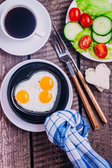 Idea for the Celebration of Valentine's Day. Healthy Breakfast - Scrambled Eggs in the Form of Hearts, black coffee and plate with vegetables cherry tomato, cucumber and salads, copy space