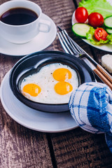 Idea for the Celebration of Valentine's Day. Healthy Breakfast - Scrambled Eggs in the Form of Hearts, black coffee and plate with vegetables cherry tomato, cucumber and salads, copy space