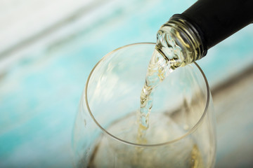 Glass of white wine being poured from bottle
