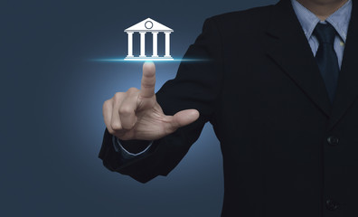 Businessman pressing bank icon over blue background, Business banking concept
