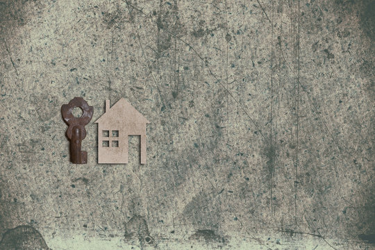model of cardboard house with key on old textured paper backgrou
