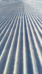 Newly groomed snow on ski slope on a sunny winter day.