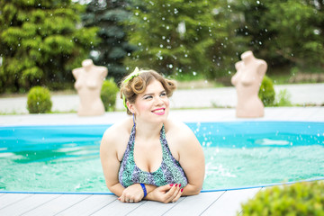 Young beautiful plus size model splashing in the pool.