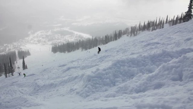 Snowboarders on the top of a mountain begins the descent