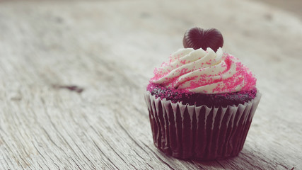 Chocolate heart on top of cupcake for valentine on old wooden ba