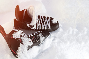 black hockey skates lying in the snow and bright sun