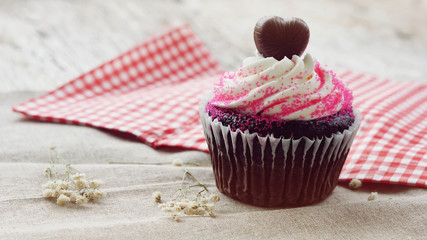 Chocolate heart on top of cupcake for valentine on old wooden ba