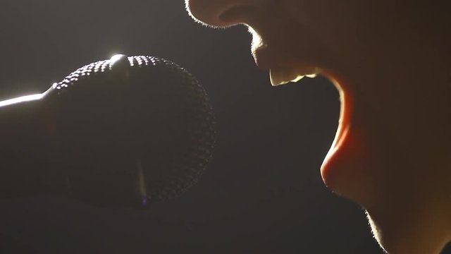 Close up footage of a woman singing to a microphone.