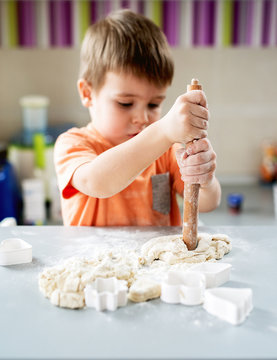 Boy making pizza dough with rolling pin.