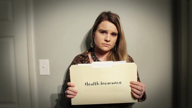 Woman holds up manilla folder with her health insurance in dramatic lighting