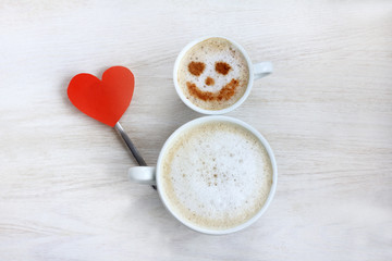cheerful snowman with congratulates loving couple/ two coffee cups with a heart symbol and a smile 