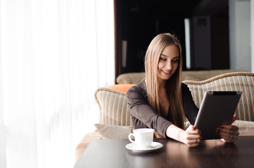 Beautiful pregnant woman using digital tablet at table in cafe