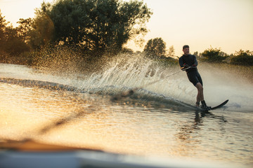 Man wakeboarding on lake behind motorboat