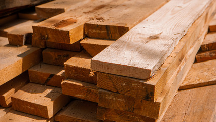 Stack of new wooden studs at a lumber yard warm color tone selective focus.