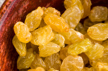 Yellow raisins close-up in a wooden bowl