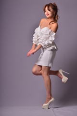 Beautiful model with long curly hair posing in an elegant Classic evening dress in the studio
