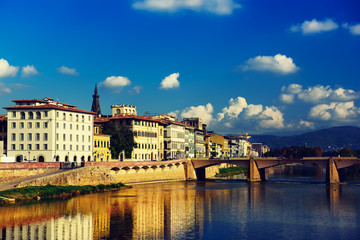 Ponte alle Grazie bridge in Florence, Italy with blue sky, clouds and reflection in the river Arno. Travel outdoor sightseeing background.
