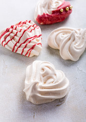 Homemade meringues in heart shape on light stone background. Valentines day concept.