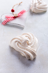 Homemade meringues in heart shape on light stone background. Valentines day concept, copy space.
