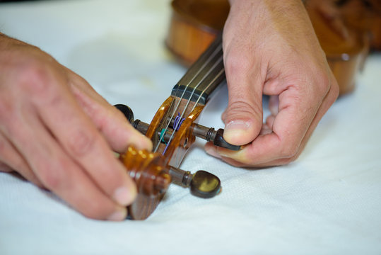 Man adjusting strings on violin