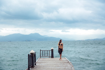 beautiful young brunette woman in black bikini posing on the beach. Sexy model portrait with perfect body. Concept of summer holidays