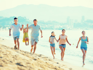 Laughing family with four children running on beach