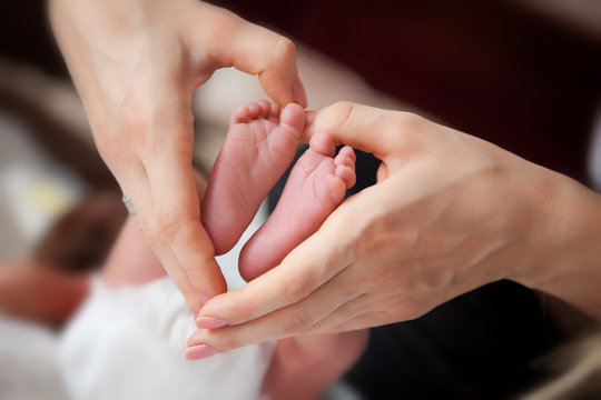 Mother makes a heart around her newborn baby boy's little feet