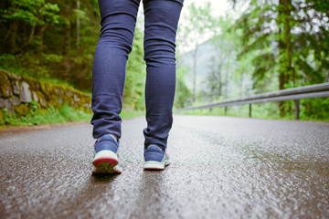 woman runner legs training on asphalt trail in the park