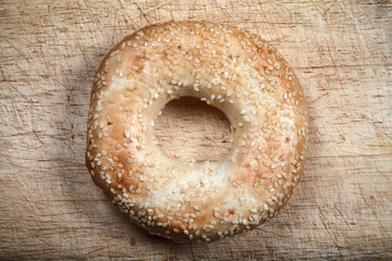 Sesame seeded bagel bread roll on a wood chopping board