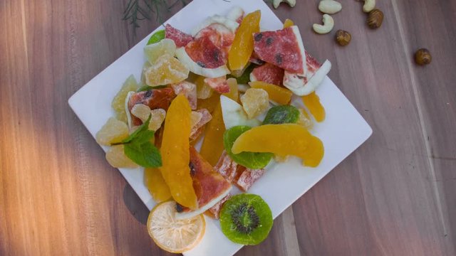 Children's hand take candied fruits from the white plate