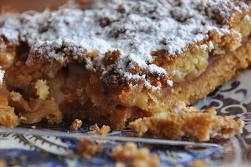 Apple pie dusted with icing sugar on the kitchen table.