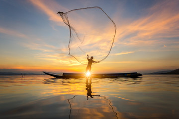Silhouette of Myanmar fisherman on wooden boat ,Myanmar fisherman in action catching freshwater...